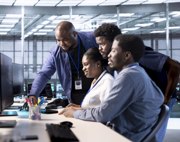 Group of technicians doing brainstorming, reconfiguring server farm to optimize it for data processing requirements. Employees working together to ensure data center equipment operates efficiently